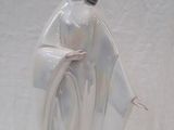 une figurine représentant une femme en robe blanche posée sur une table