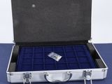 an open silver briefcase with blue velvet linings on a blue surface