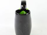 a black cup with a green handle on a white background