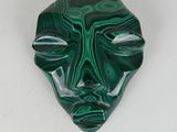 a close up of a green and black mask on a white surface