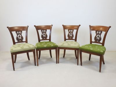 four chairs with green upholstered cushions and a wooden frame