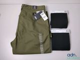 un pantalon vert pour homme et un pantalon noir posés sur une table blanche