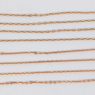 une collection de chaînes en or posées sur une surface blanche