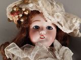 a close up of a doll wearing a hat and dress