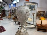 un vase en argent posé sur un socle dans une pièce
