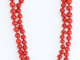 a red beaded necklace with a gold clasp on a white background