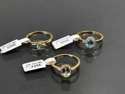 three gold rings with blue topaz and diamonds on them