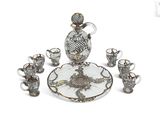 a glass and silver plate with a glass decanter and cups on it