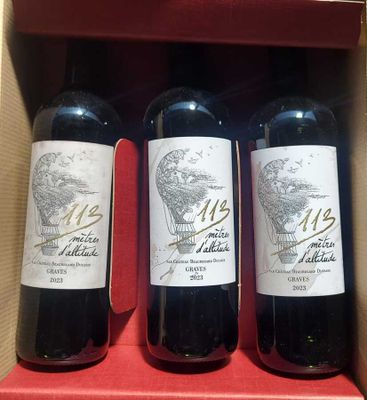 three bottles of red wine in a cardboard box on a table