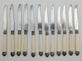six knives are lined up in a row on a white surface