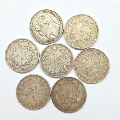six types différents de pièces d'argent sur une surface blanche