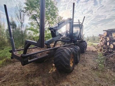 un tracteur garé à côté d'un tas de bûches