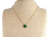 un collier en or avec un pendentif en forme de trèfle vert sur un mannequin