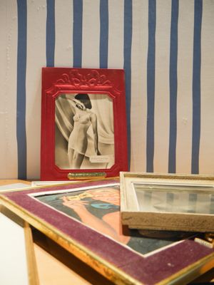 une photo représentant une femme, dans un cadre rouge, posée sur une table à côté d'une photo représentant une femme en robe blanche