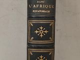 un vieux livre noir aux tranches dorées posé sur une table