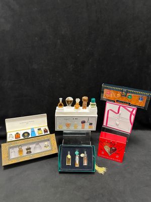 quatre flacons de parfum miniatures et un coffret de parfum sur fond noir