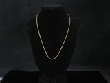 a gold chain necklace on a black mannequin stand