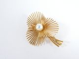 an image of a gold brooch with a pearl in the center