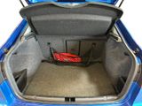 the trunk of a blue car with a basket of luggage in it