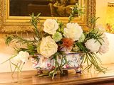 un vase de fleurs posé sur une table devant un tableau