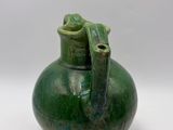 a green vase with a handle on a white surface