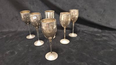 quatre verres à vin argentés à pied sur fond noir