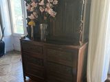 a dresser with flowers on top of it in a living room