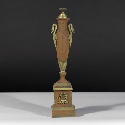 un vase antique en bronze posé sur un socle, sur fond noir
