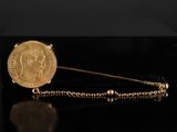une image représentant une broche en forme de pièce d'or entourée d'une chaîne