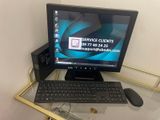 un ordinateur posé sur un bureau en verre, avec un clavier et une souris