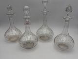 four glass decantes with a bird on the top of them