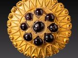 deux paires de boutons en verre doré et noir sur une surface réfléchissante