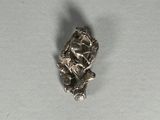 une petite figurine en argent représentant une femme assise sur une branche d'arbre
