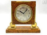 a small wooden clock on a stand with a white background