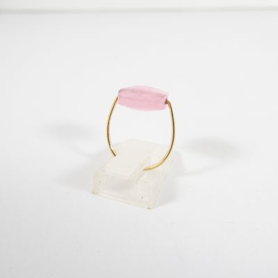 a gold ring with a pink stone on a clear base