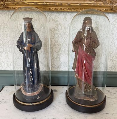 deux figurines posées sous un dôme en verre sur une table