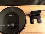 un robot noir posé sur une table en bois, à côté d'un téléphone portable