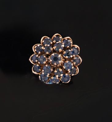a close up of a gold ring with blue stones on a black surface