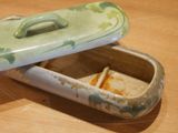 a green and white container with a lid on a wooden table