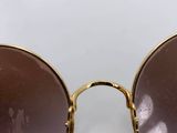 gold sunglasses with brown lenses on a white surface