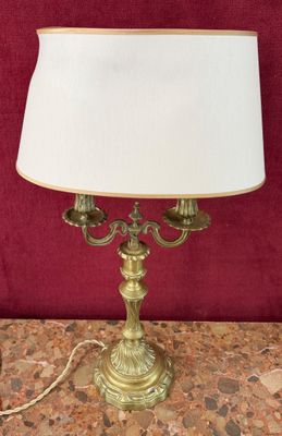 a brass table lamp with a white shade on top of it