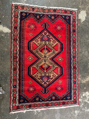 a red and blue rug sitting on top of a cement floor
