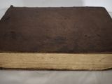 an old book sitting on top of a white cloth covered table