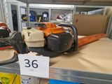 plusieurs tronçonneuses posées sur une étagère dans un magasin, avec une étiquette de prix