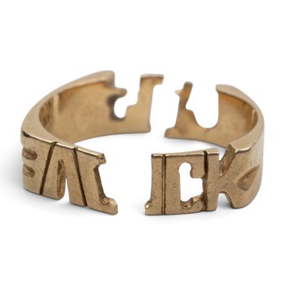 un gros plan d'une bague en or sur laquelle sont gravées des lettres