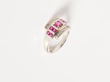 a close up of a pink and white diamond ring on a white surface