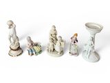 Plusieurs figurines de tailles et de formes variées sont disposées sur une surface blanche