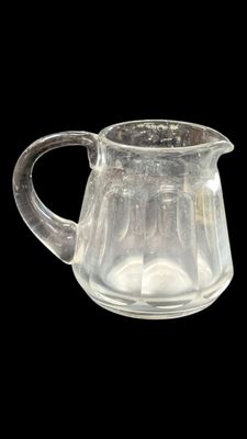 un pichet en verre transparent muni d'une anse, sur fond noir