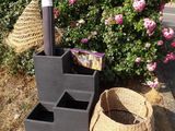 a basket and a toilet brush on the ground next to a bush