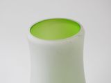 a white vase with a green top on a white table